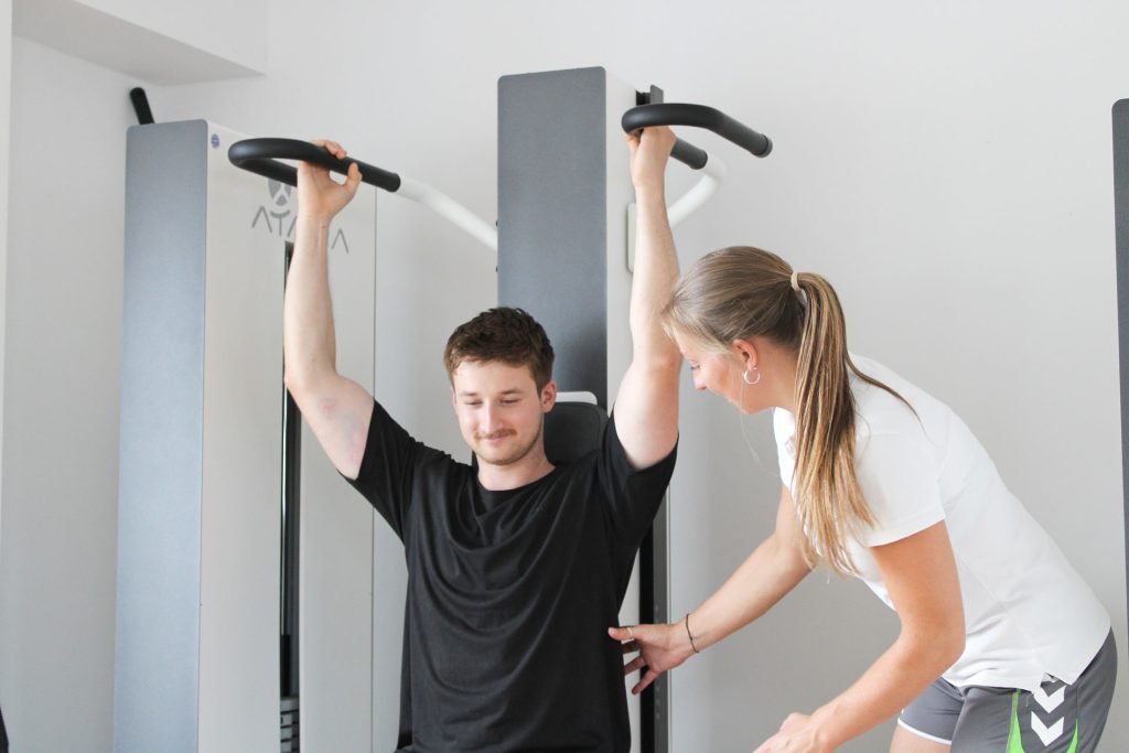 Eine Sportwissenschaftlerin gibt dem Patienten ein T-Rena Geräteeinweisung
